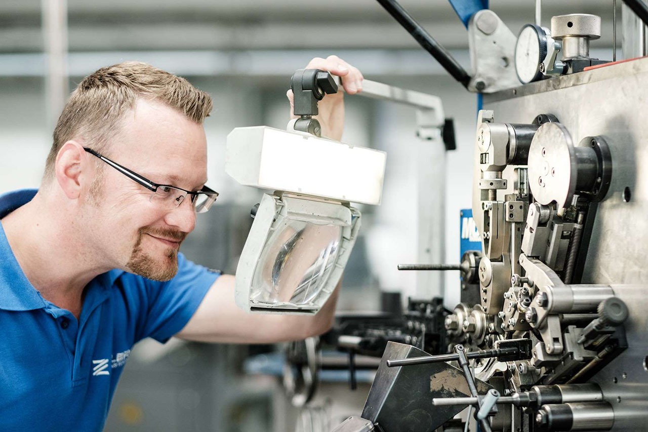 Mitarbeiter prüft eine Feder auf ihre Festigkeit und Funktionalität im Testbereich.